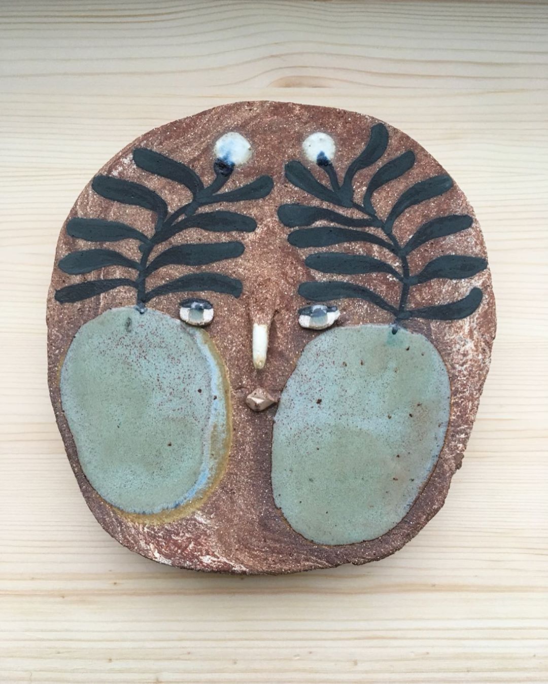 Ceramic face with plant motif