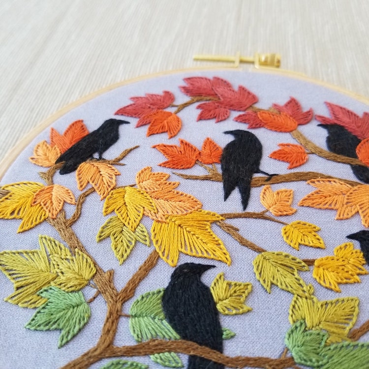 Embroidery pattern featuring black birds on tree with fall leaves
