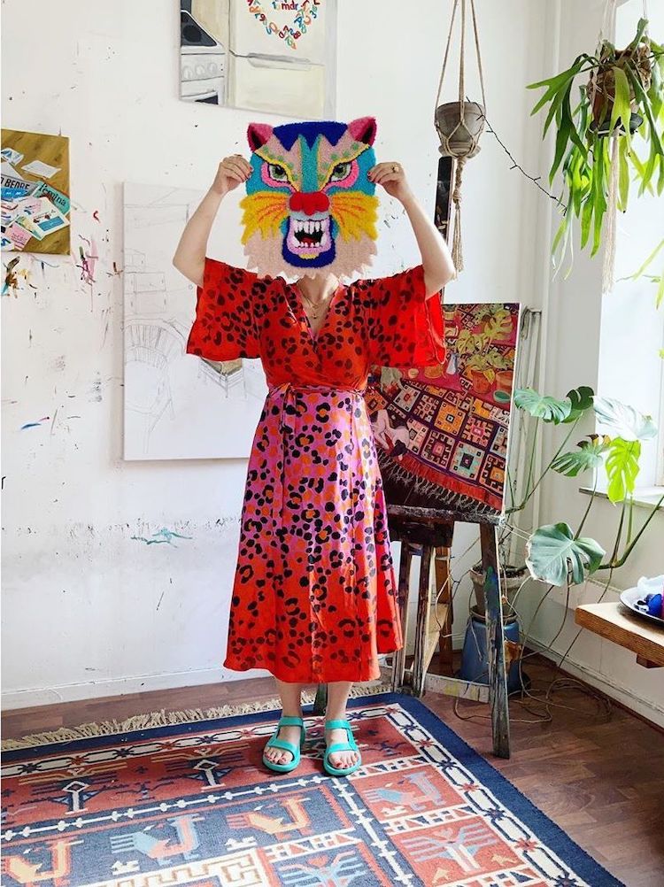 Artist Ina Dyreborg holding her tufted tiger art up to her head