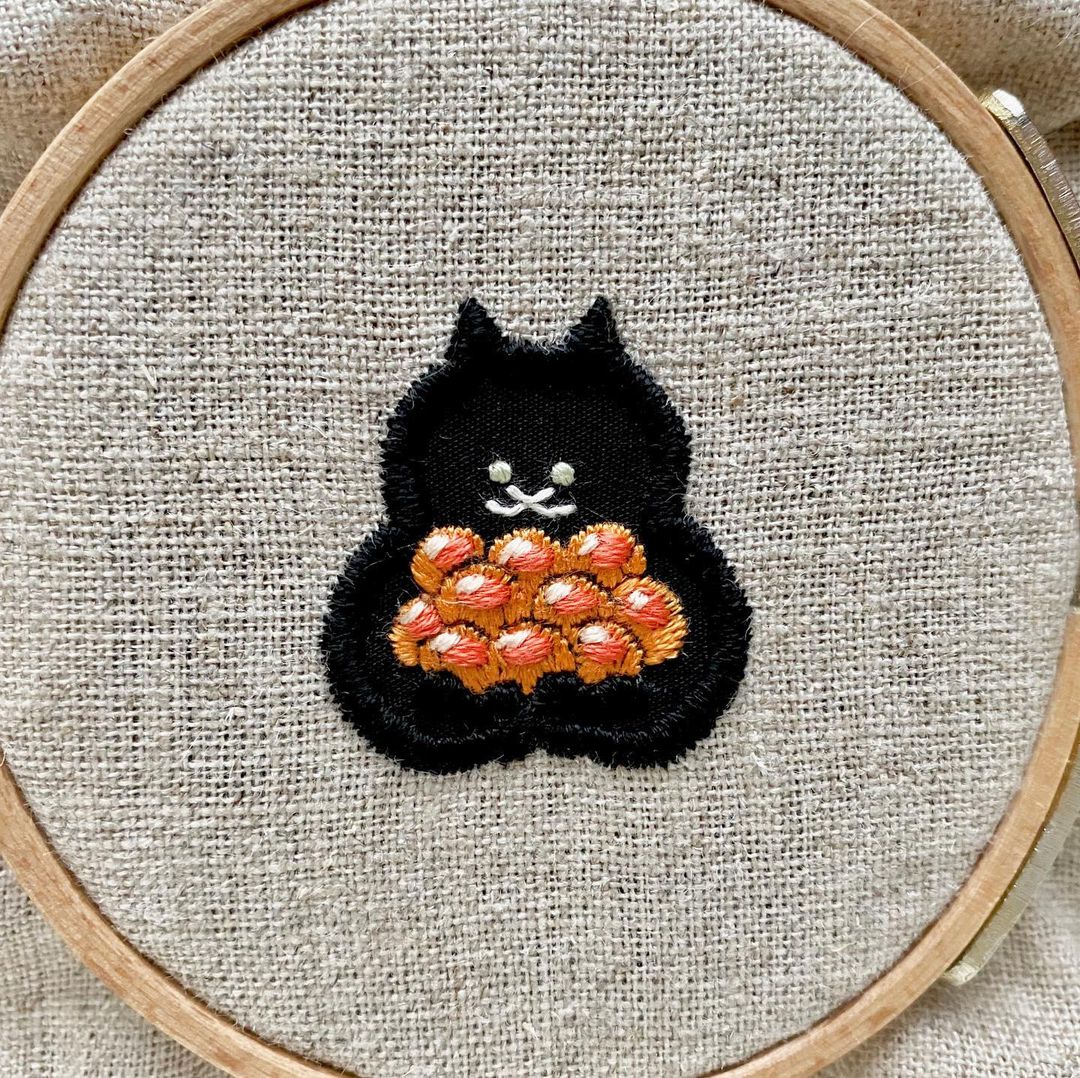 Embroidery of a Cat Carrying a Sushi